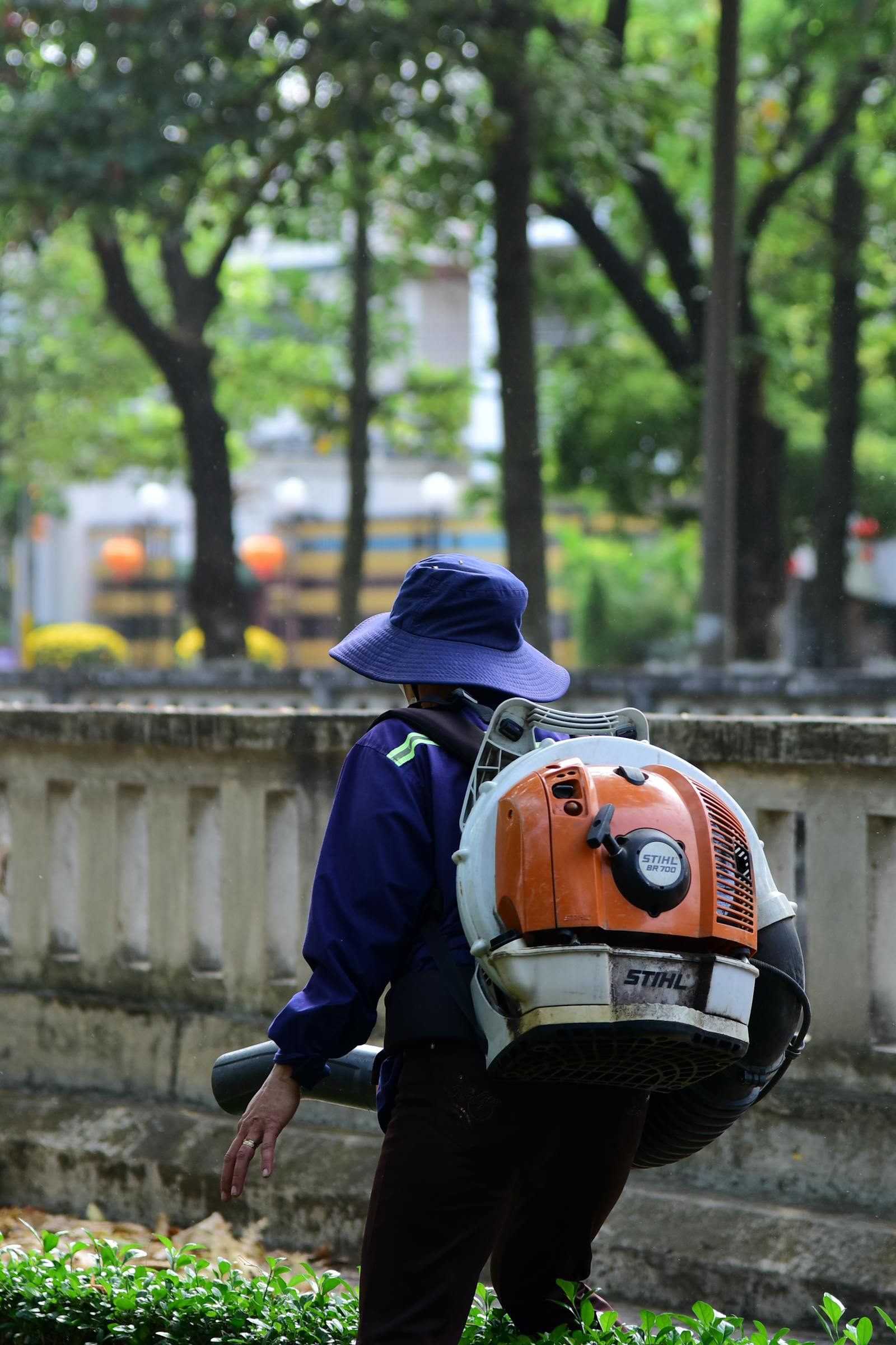Operator with a backpack blower clearing clippings off a walkway.